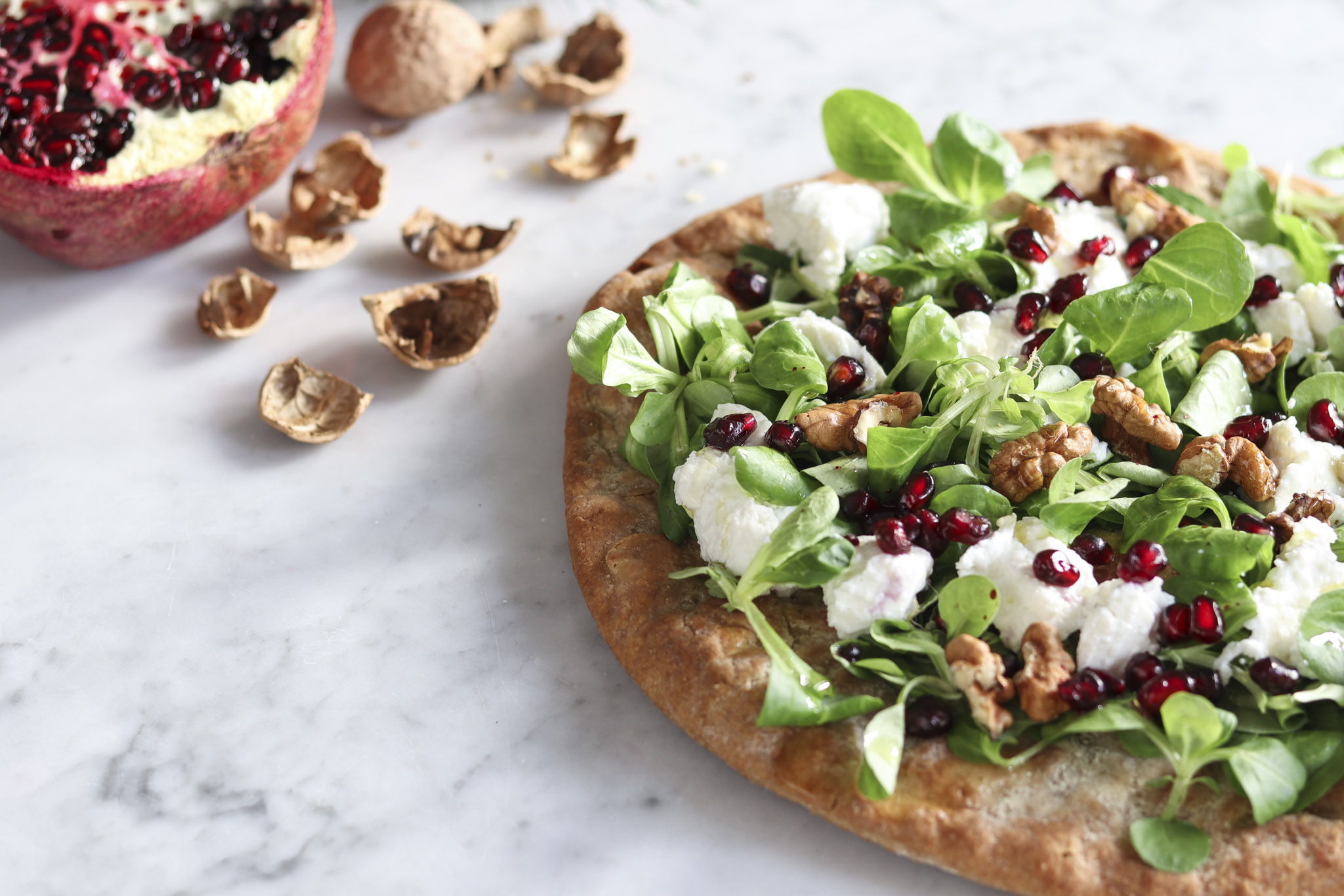 Pizza con melograno, ricotta e noci, ricetta per le feste.